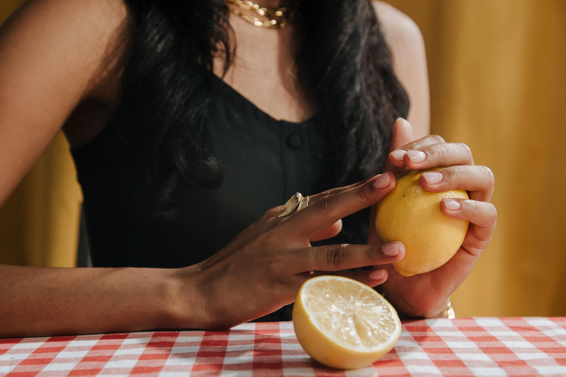 Donna che tiene un limone fresco al tavolo da pranzo