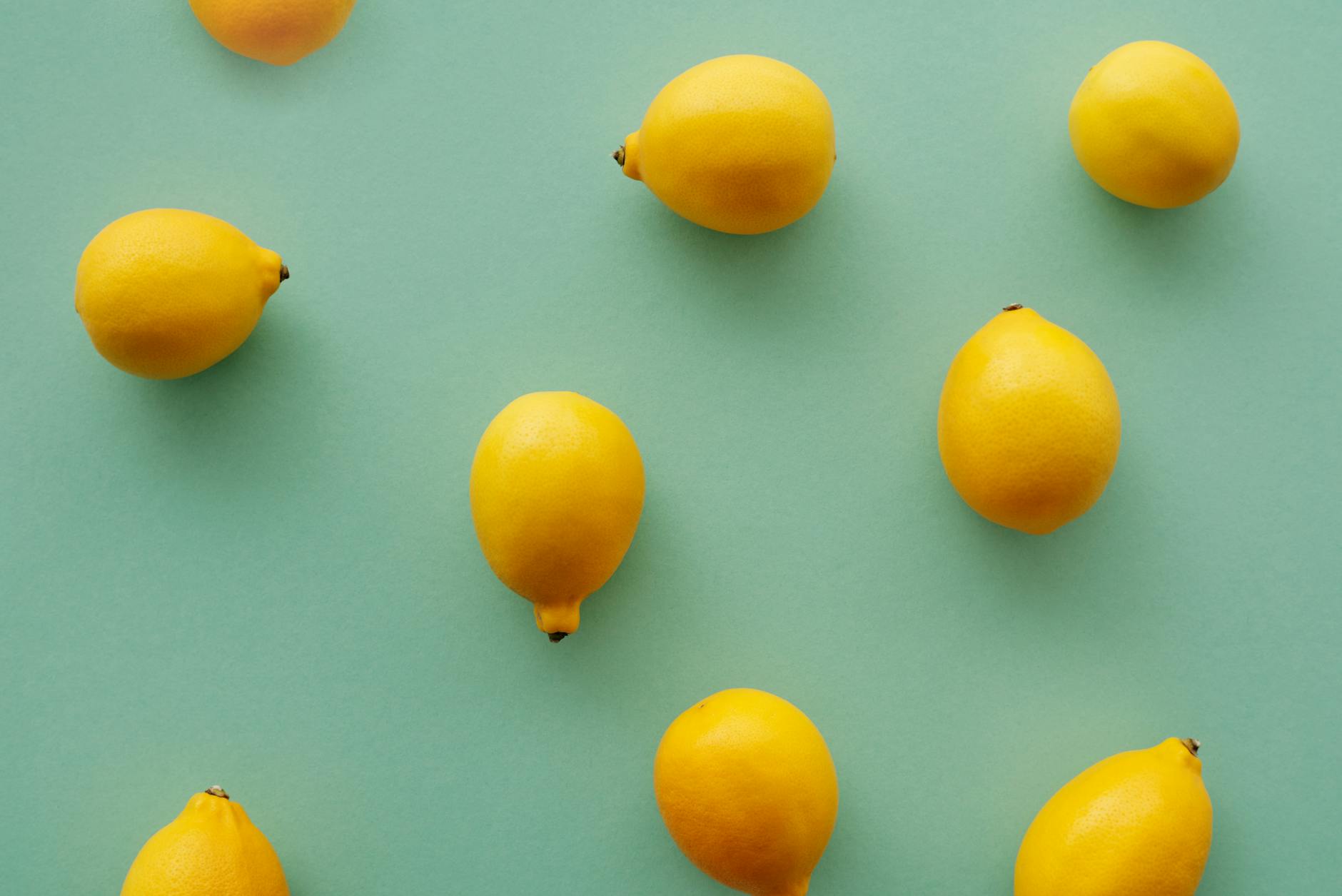 Limoni freschi disposti su sfondo verde pastello, creando una composizione fresca e vibrante di flat lay