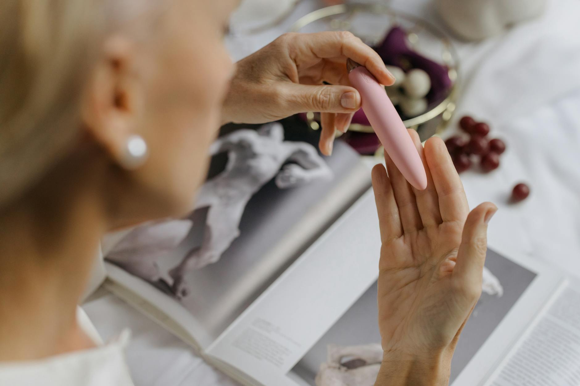 Donna che tiene in mano vibratori in silicone blu e rosa, con uno sguardo consapevole e sereno