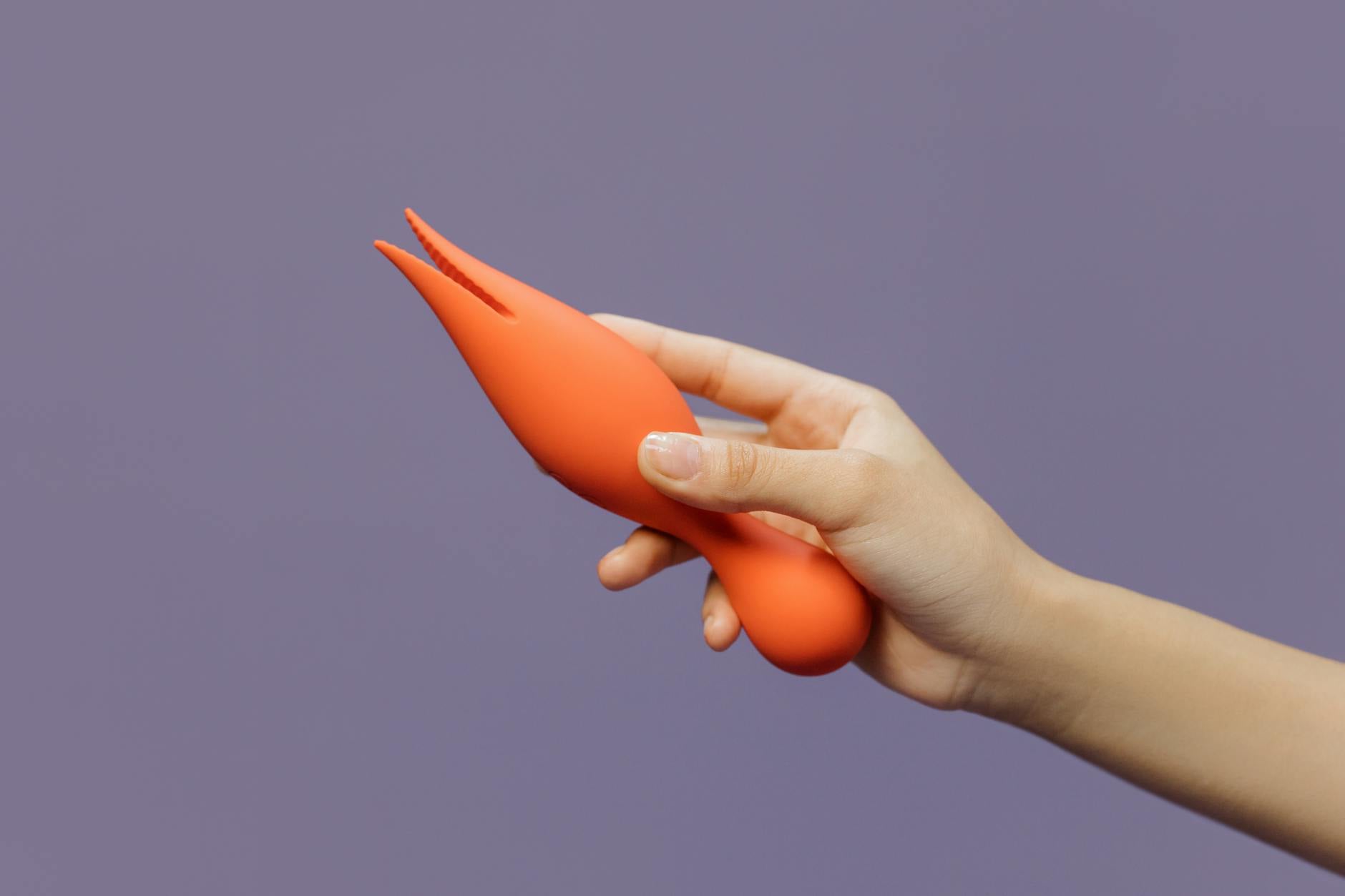 Mano che tiene un vibratore moderno su uno sfondo minimalista, simbolo di intimità consapevole